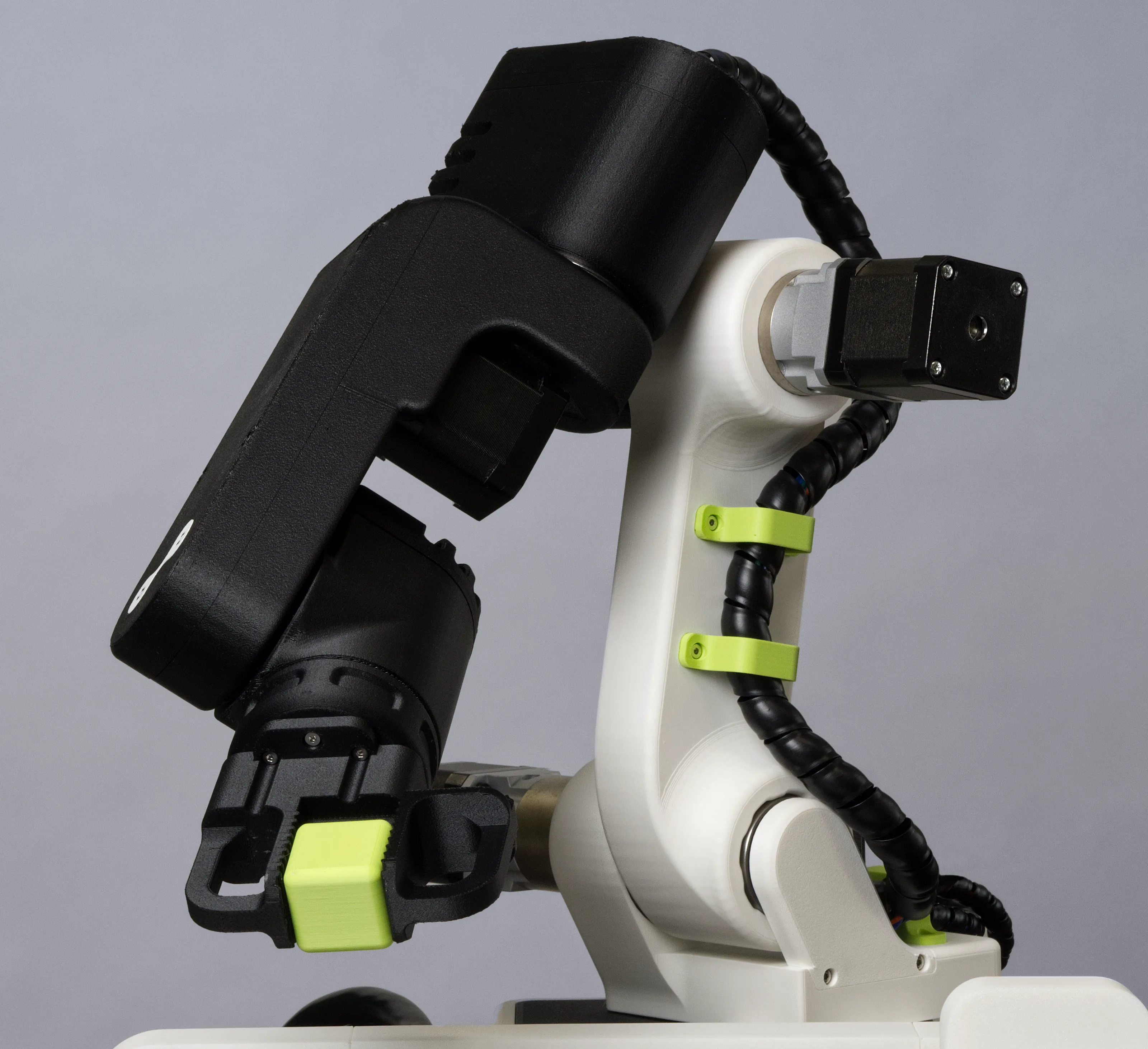 A photo of the 3D-printed robot GK-RA with gripper and a plastic cube moving to the left.